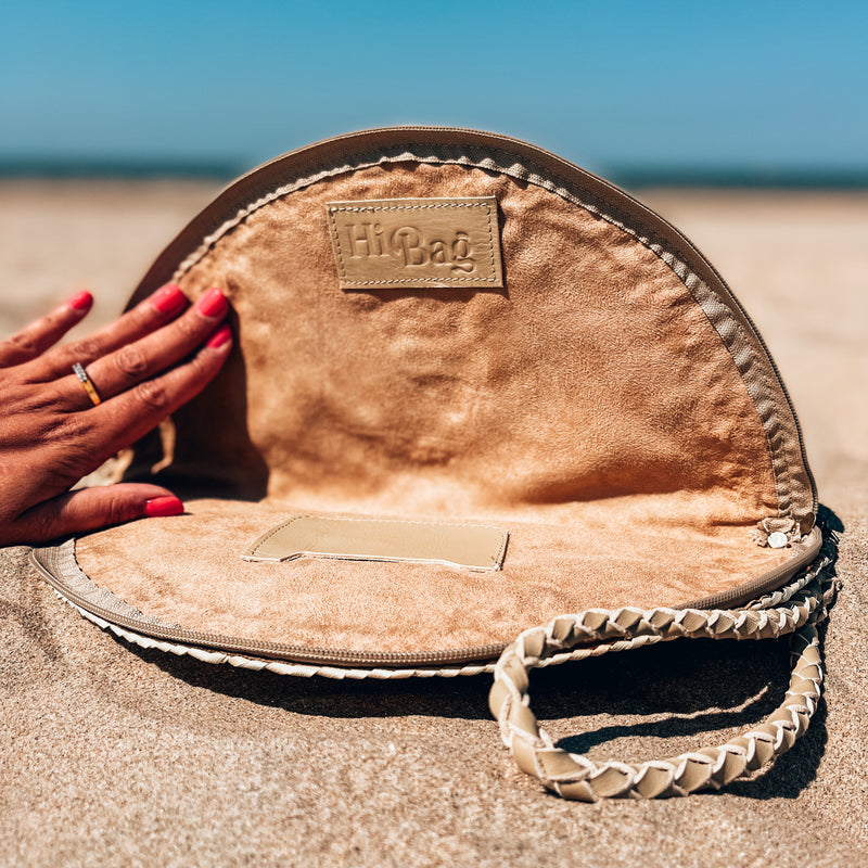 Geopende rieten clutch met leren logo, binnenkant zichtbaar