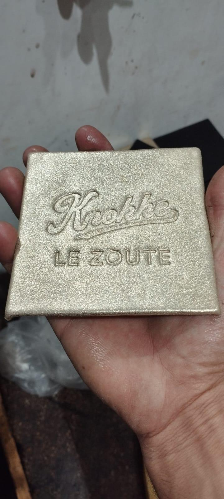 Goudkleurig leren label met Knokke Le Zoute logo