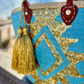 Boho rieten strandtas Aztec goud en turquoise, close-up met gouden tassel