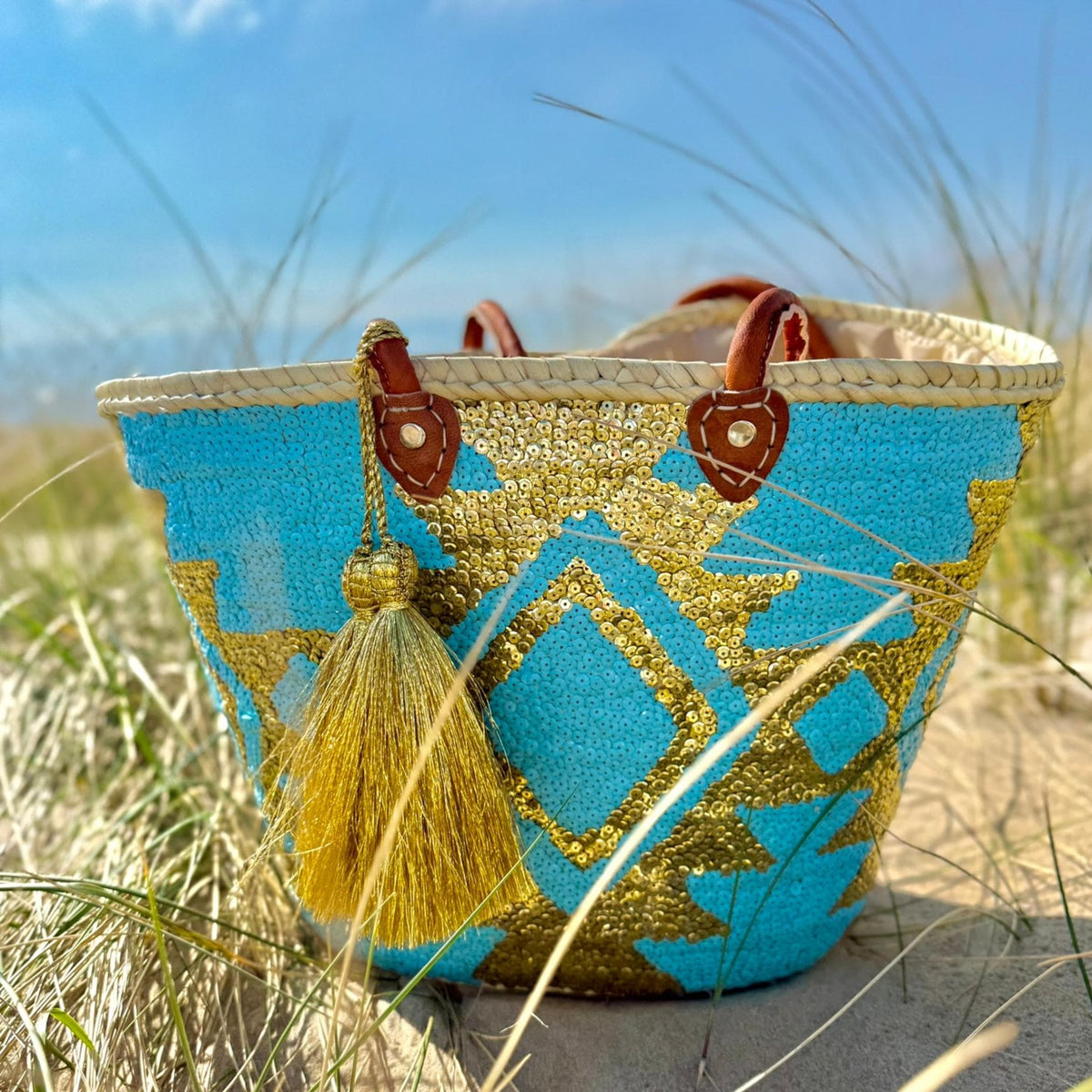 Boho rieten strandtas Aztec goud en turquoise, vooraanzicht in de duinen
