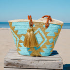 Boho rieten strandtas Aztec goud en turquoise, vooraanzicht op een houten bank op het strand