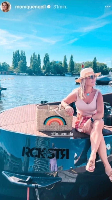 Monique Noell op een boot met een rieten tas met regenboog van Bohemida