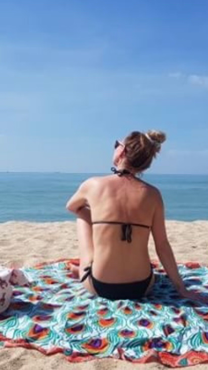 Reisblogger Rebecca op een kleurrijk strandlaken van Bohemida aan zee