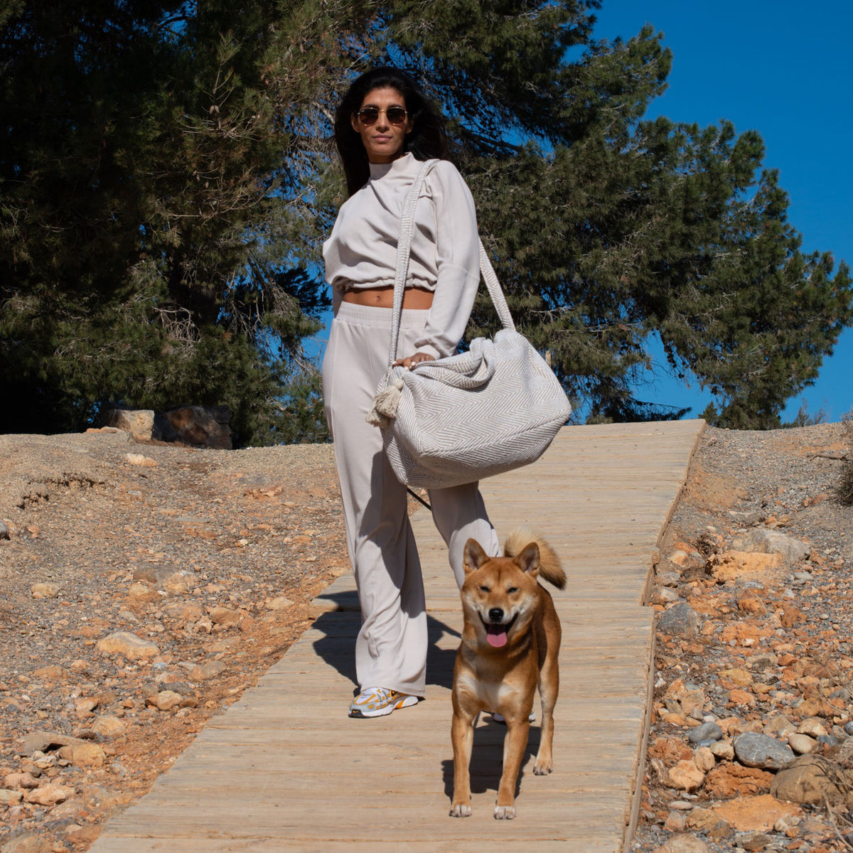 Gestreepte travel bag beige, gedragen op een trap in de zon
