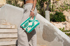 Hippie clutch en toilettas groen en beige in de hand op witte trap
