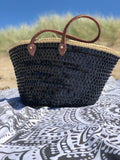 Grote rieten strandtas met pailletten zwart, op een strandlaken in de duinen