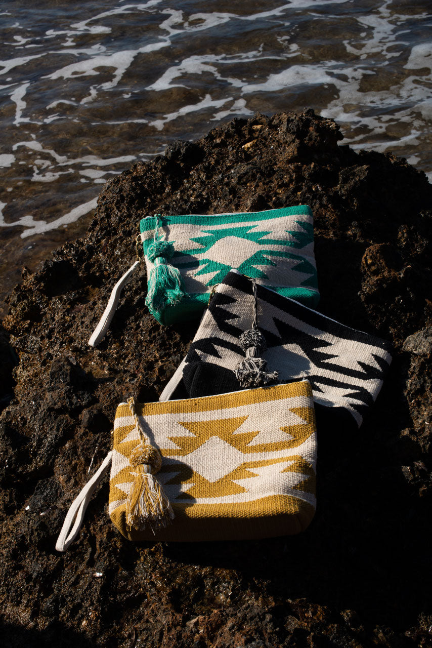 Hippie clutch and toiletry bag ochre and beige, on a dark rock