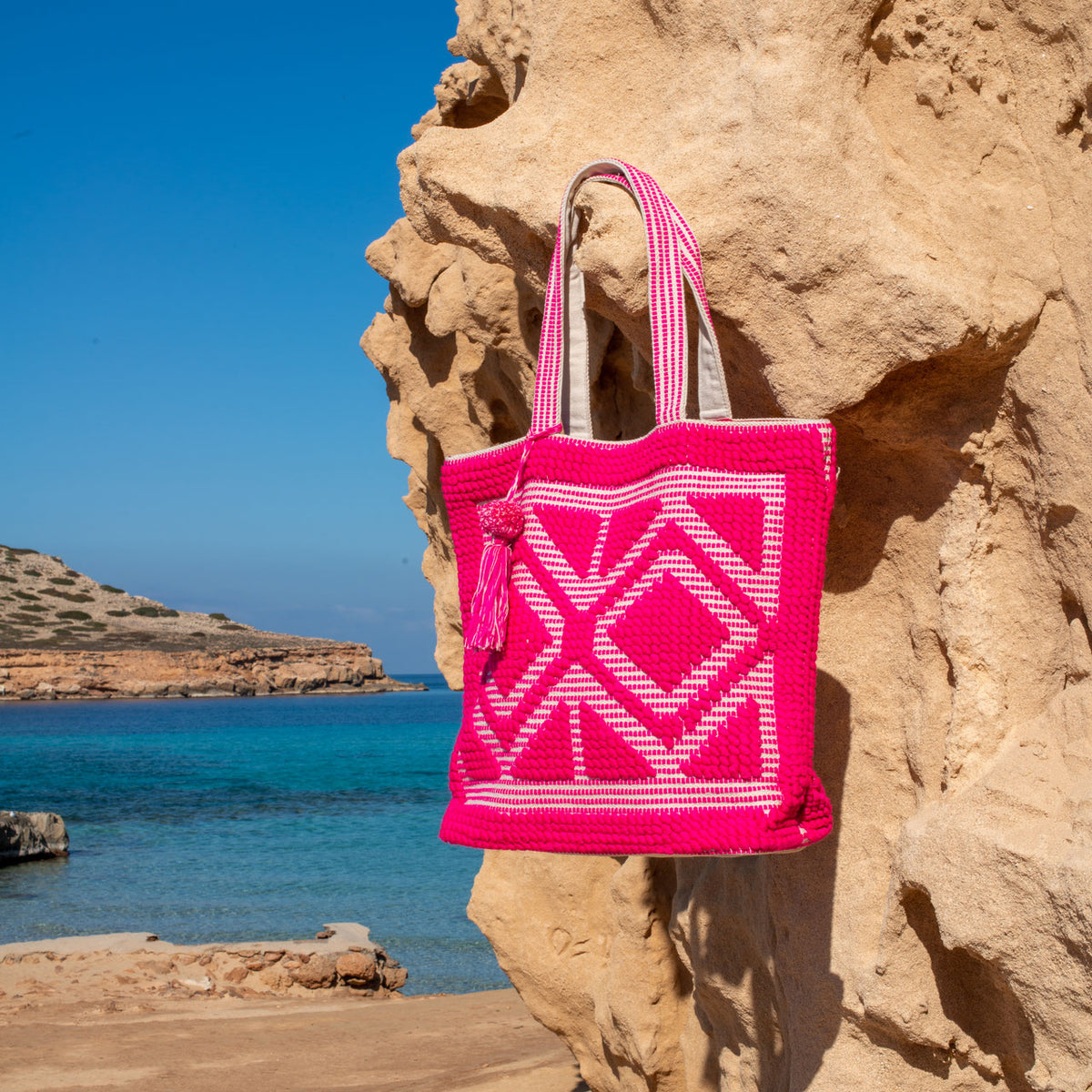 Ibiza strandtas fuchsia, hangend aan een rots bij zee