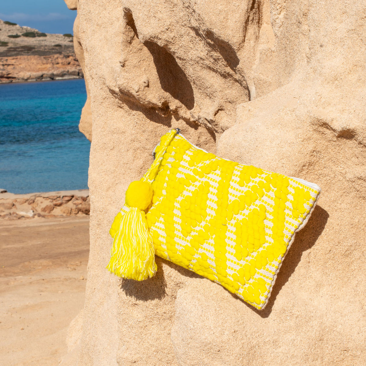 Ibiza toiletry bag and clutch yellow, close up on a rock
