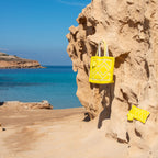 Ibiza toilettas en clutch geel, samen met de Ibiza strandtas aan een rots bij zee