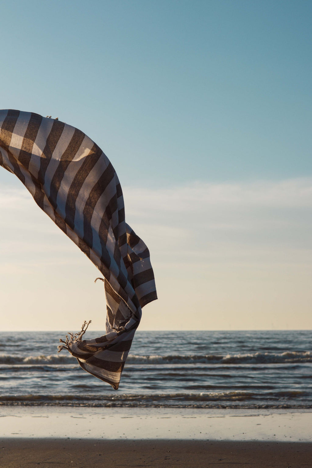 Luxury XXL hammam towel beige striped billowing in the wind above the sea