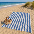 Luxe XXL hamamdoek blauw gestreept 240x210 cm, uitgespreid op het strand met een rieten tas