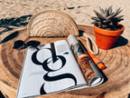 Basic rattan clutch natural with a magazine on the sand
