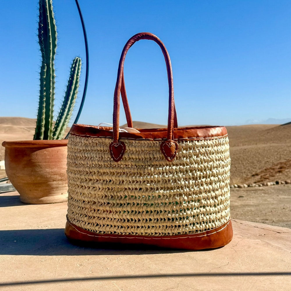 Rieten handtas met leren draaghengsels, naast een cactus in de zon