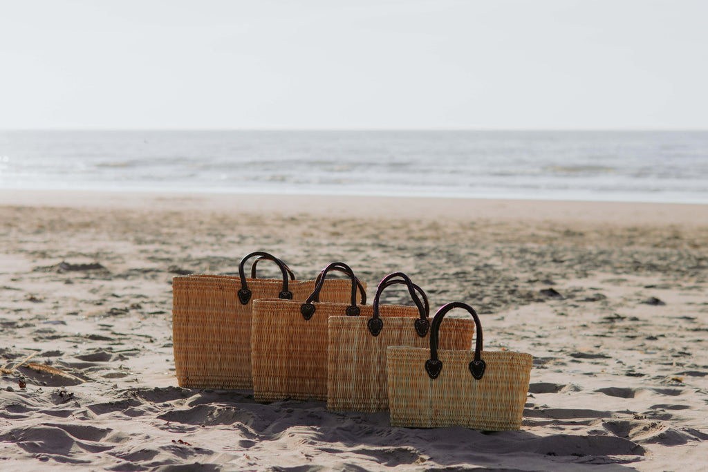Rieten shopper Faria in vier maten naast elkaar op het strand