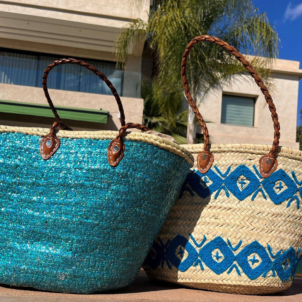 Rieten shopper met kleurrijk borduurwerk blauw, samen met andere kleuren bij het zwembad