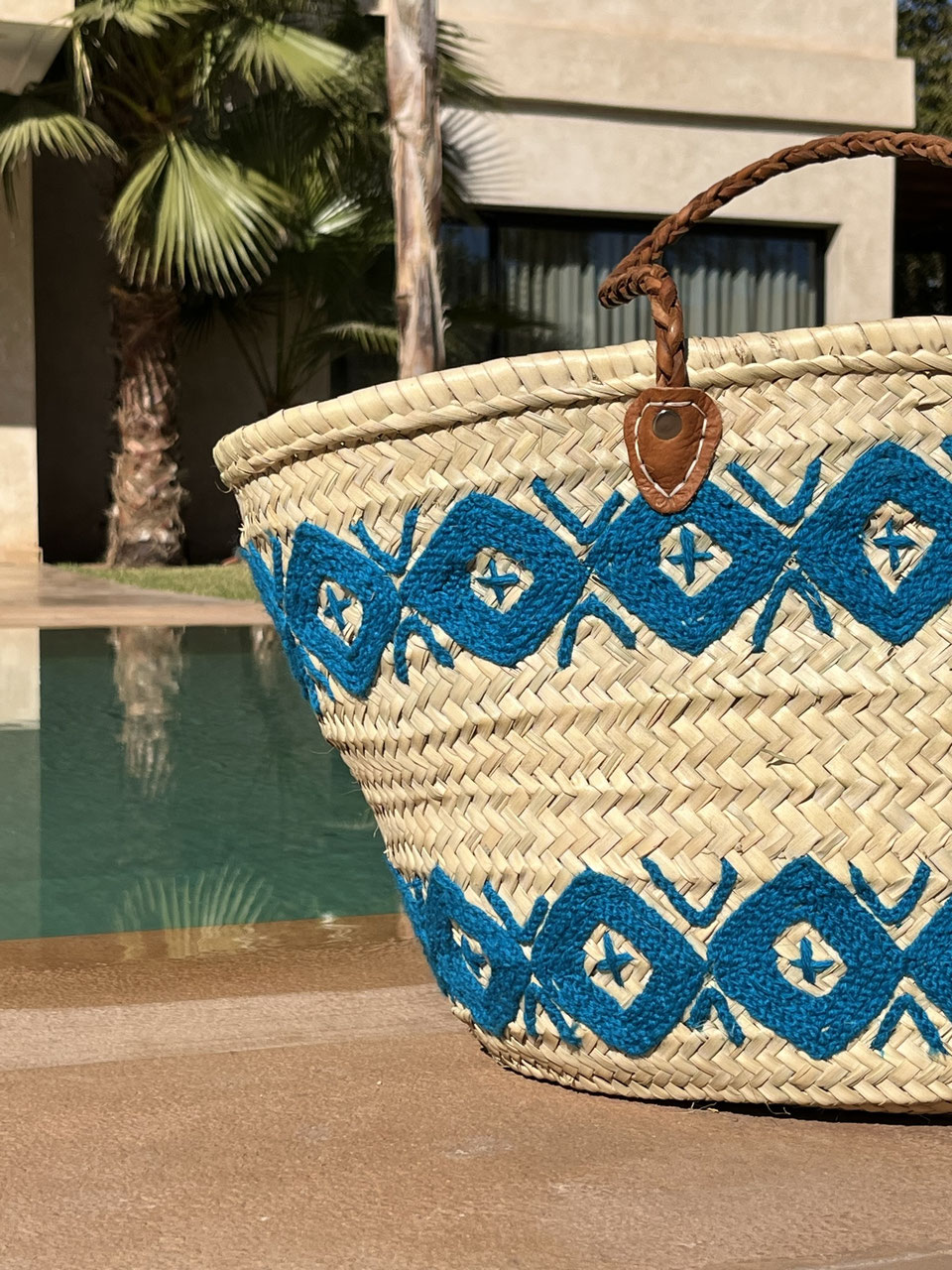 Rieten shopper met kleurrijk borduurwerk blauw, vooraanzicht in de zon
