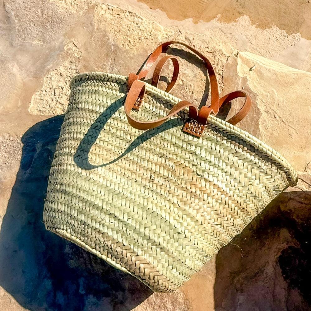 Rattan shopper with long and short leather handles, outside on a stone wall