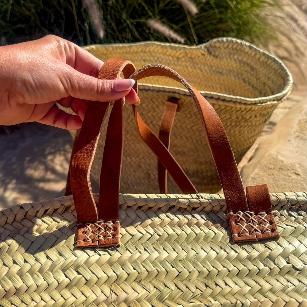 Rattan shopper with long and short leather handles, detail of the short leather handles in the hand