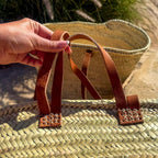 Rattan shopper with long and short leather handles, detail of the short leather handles in the hand