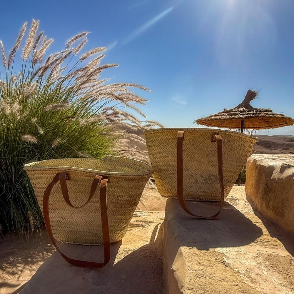 Rattan shopper with long and short leather handles, several bags in the sun by a parasol