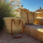 Rattan shopper with long and short leather handles, on a wall in the sun