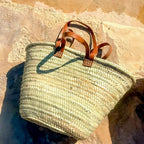 Rattan shopper with long and short leather handles, front view in the sun