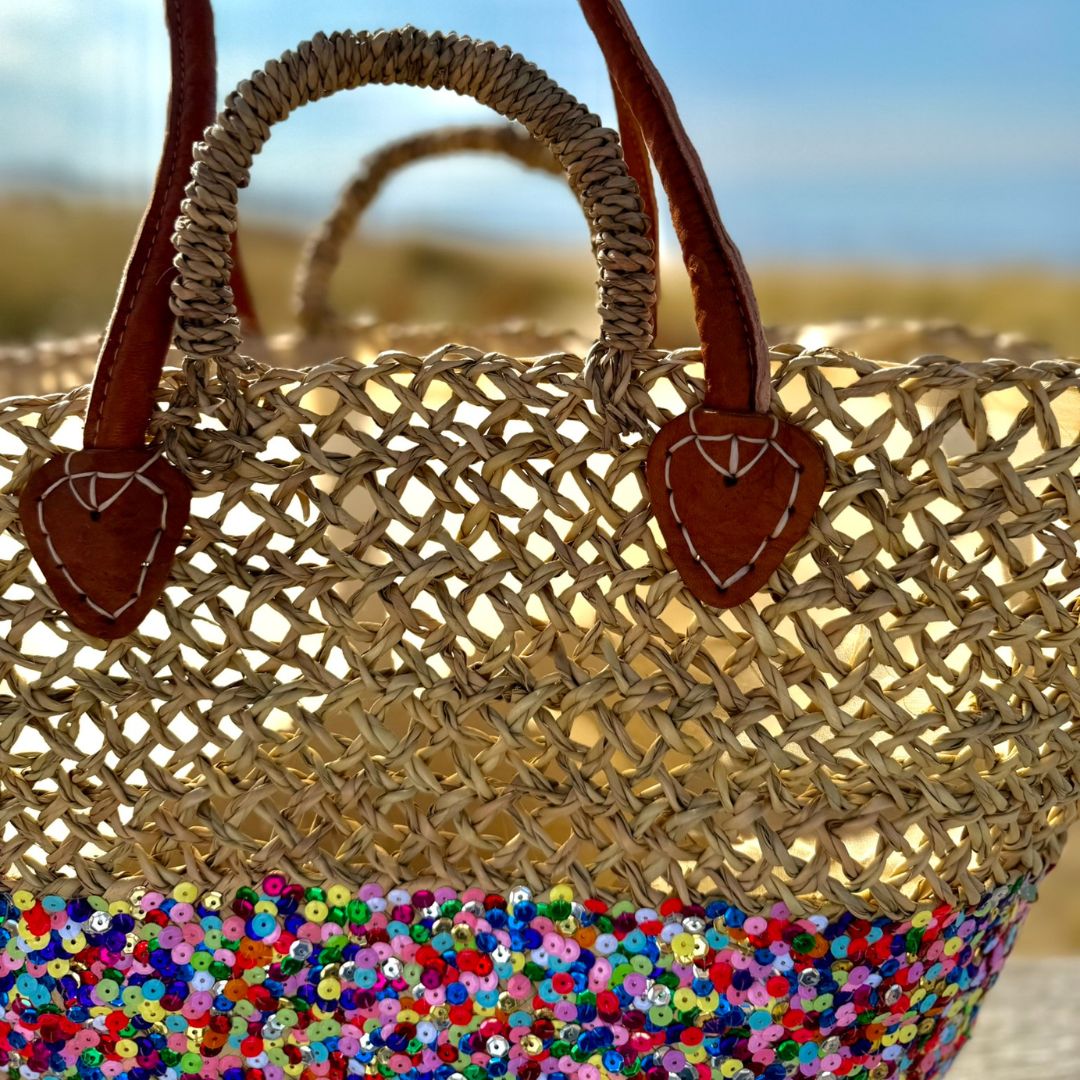 Rieten strandtas Dounia Multi, close-up van het open vlechtwerk, de leren hengsels en kleurrijke pailletten