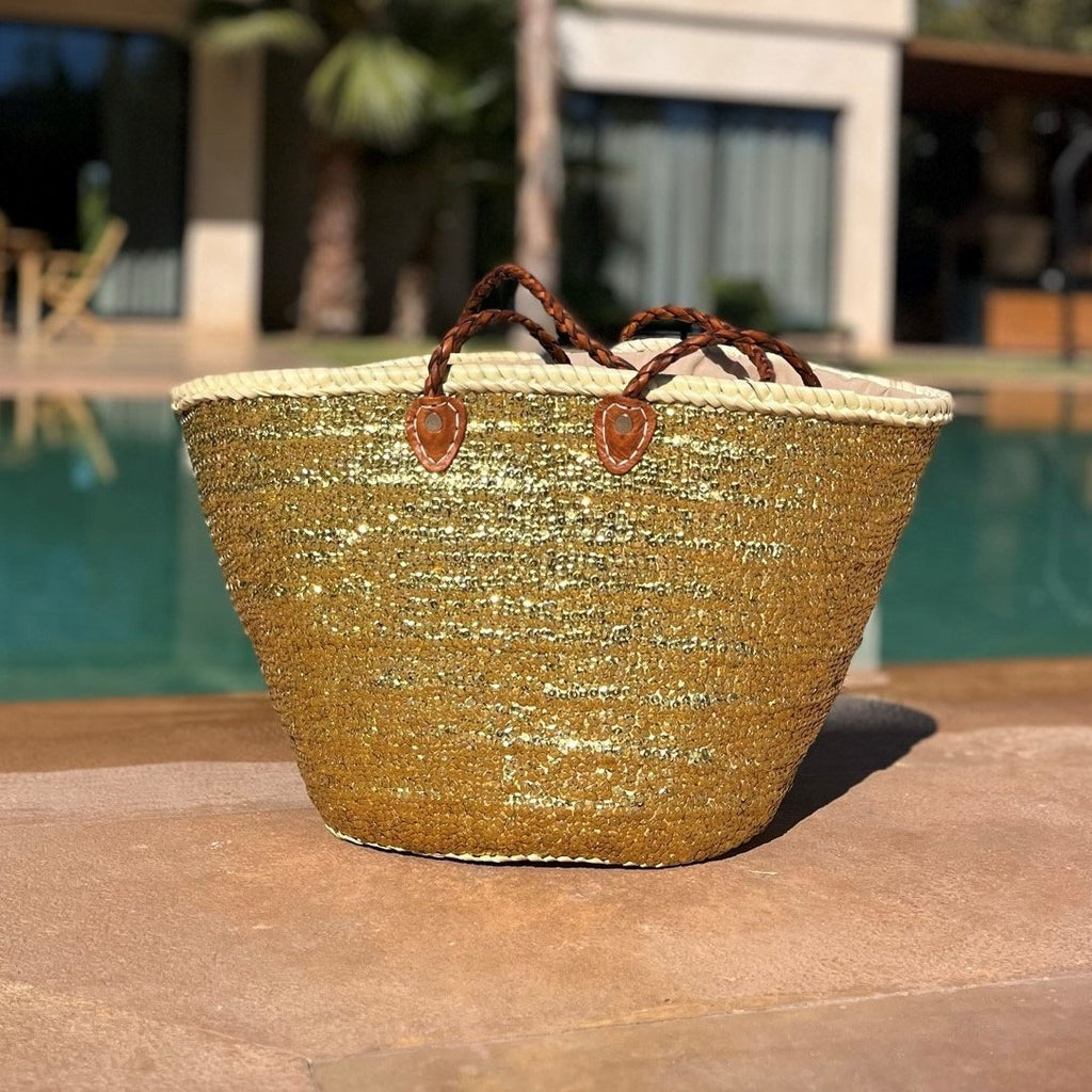 Rieten strandtas met pailletten goud, op een terras in de zon
