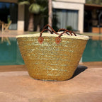 Rieten strandtas met pailletten goud, op een terras in de zon