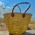 Rieten strandtas met pailletten goud, vooraanzicht in de zon