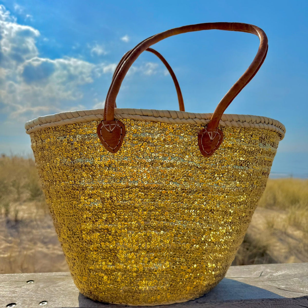 Rieten strandtas met pailletten goud, vooraanzicht in de zon
