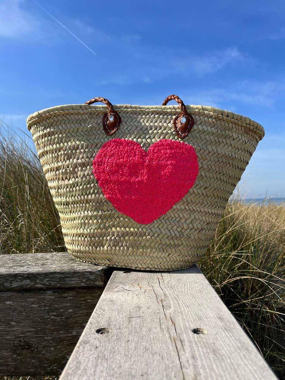 Rieten strandtas met pailletten Hart roze, op een houten steiger