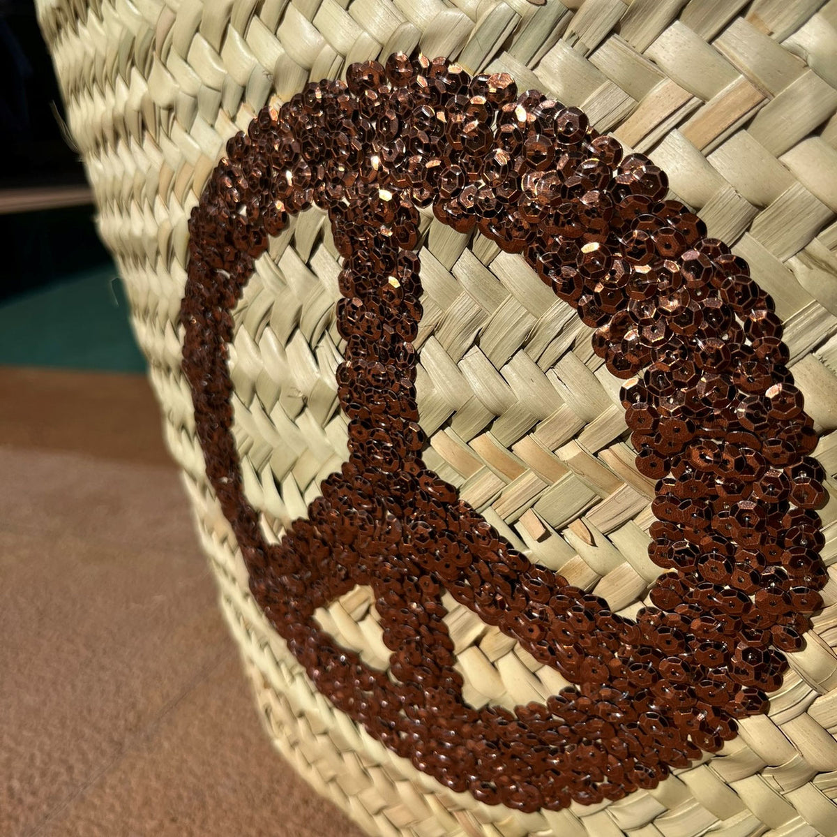 Rieten strandtas met pailletten Peace bruin, close-up van het peaceteken