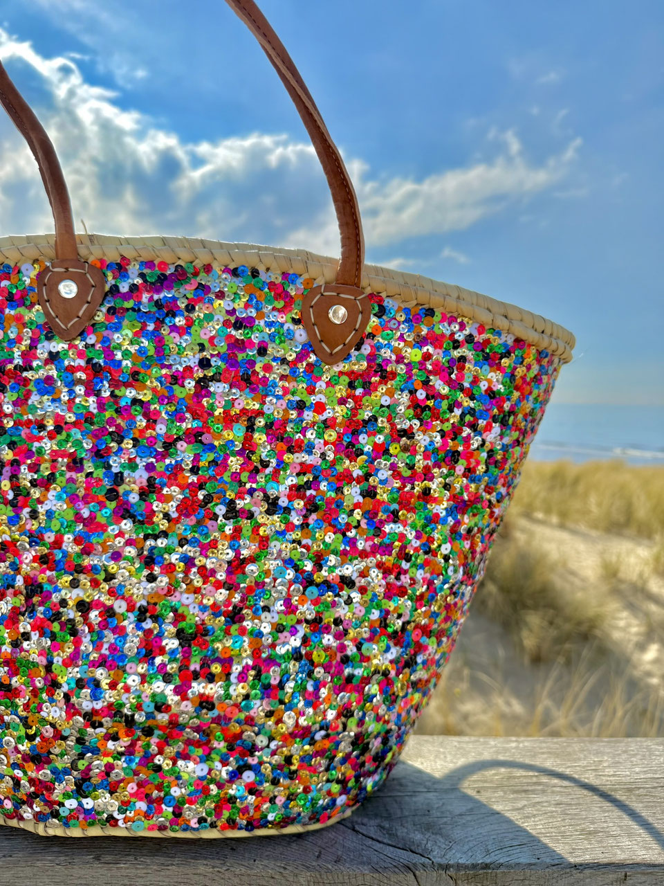 Straw beach bag with sequins pink, purple and green, in the dunes