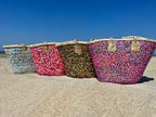 Straw beach bag with sequins pink, red and white, together with other sequin bags on the beach