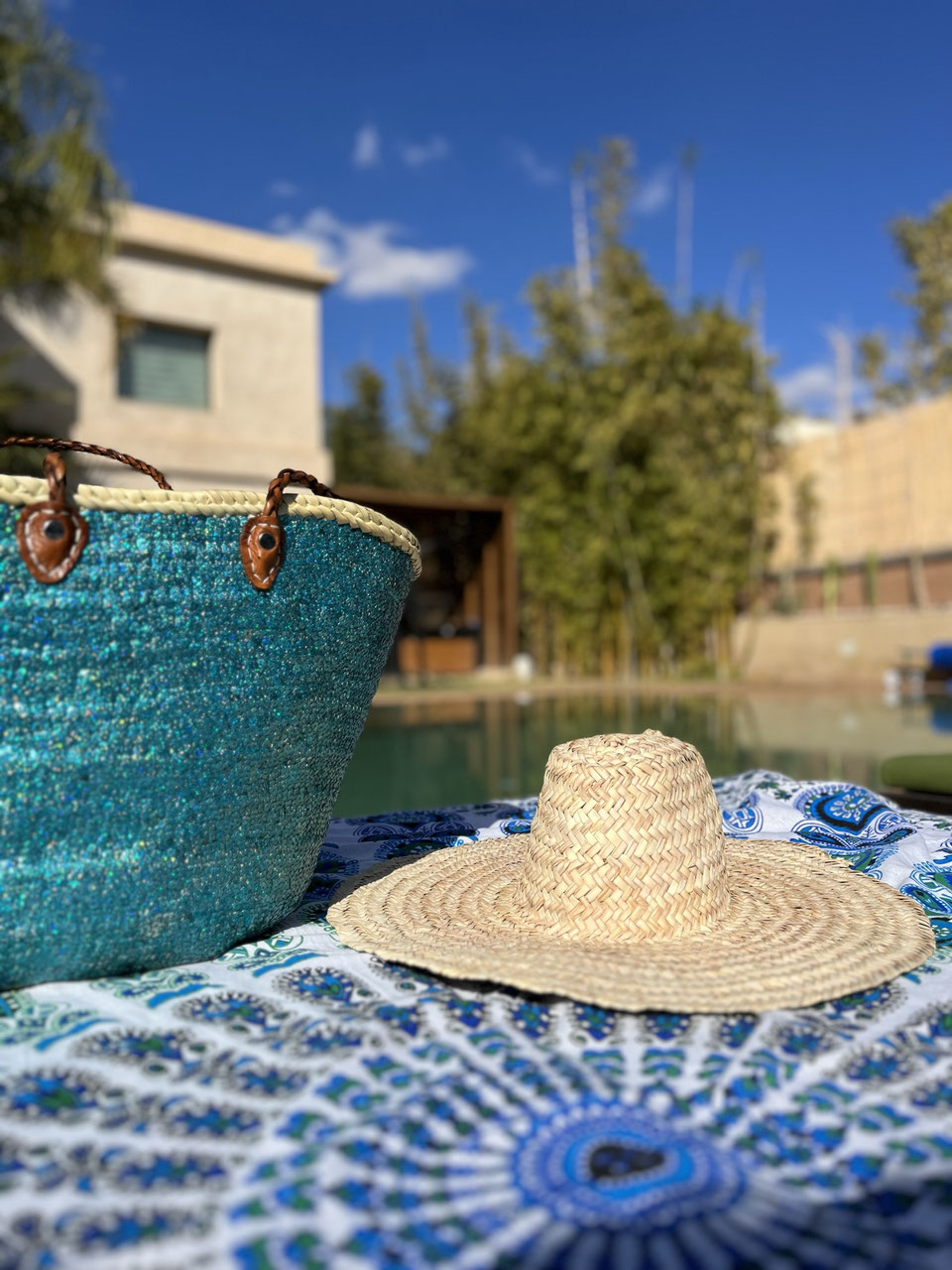 Rieten strandtas met pailletten turquoise, met strohoed op een strandlaken