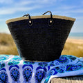 Rieten strandtas met pailletten zwart, op een strandlaken