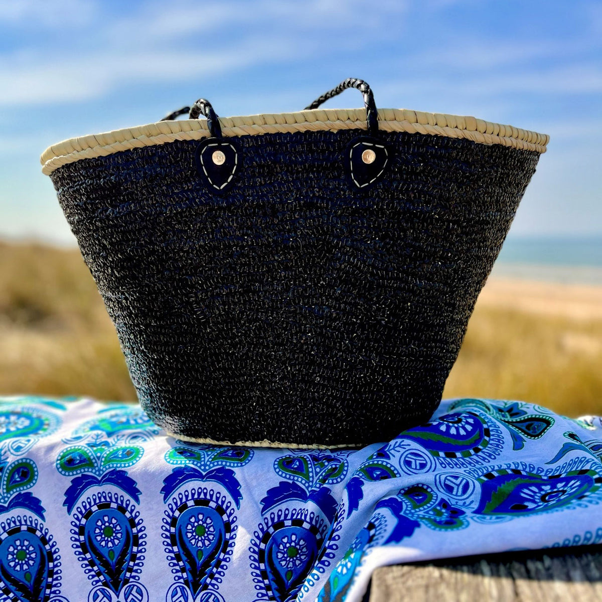 Rieten strandtas met pailletten zwart, op een strandlaken