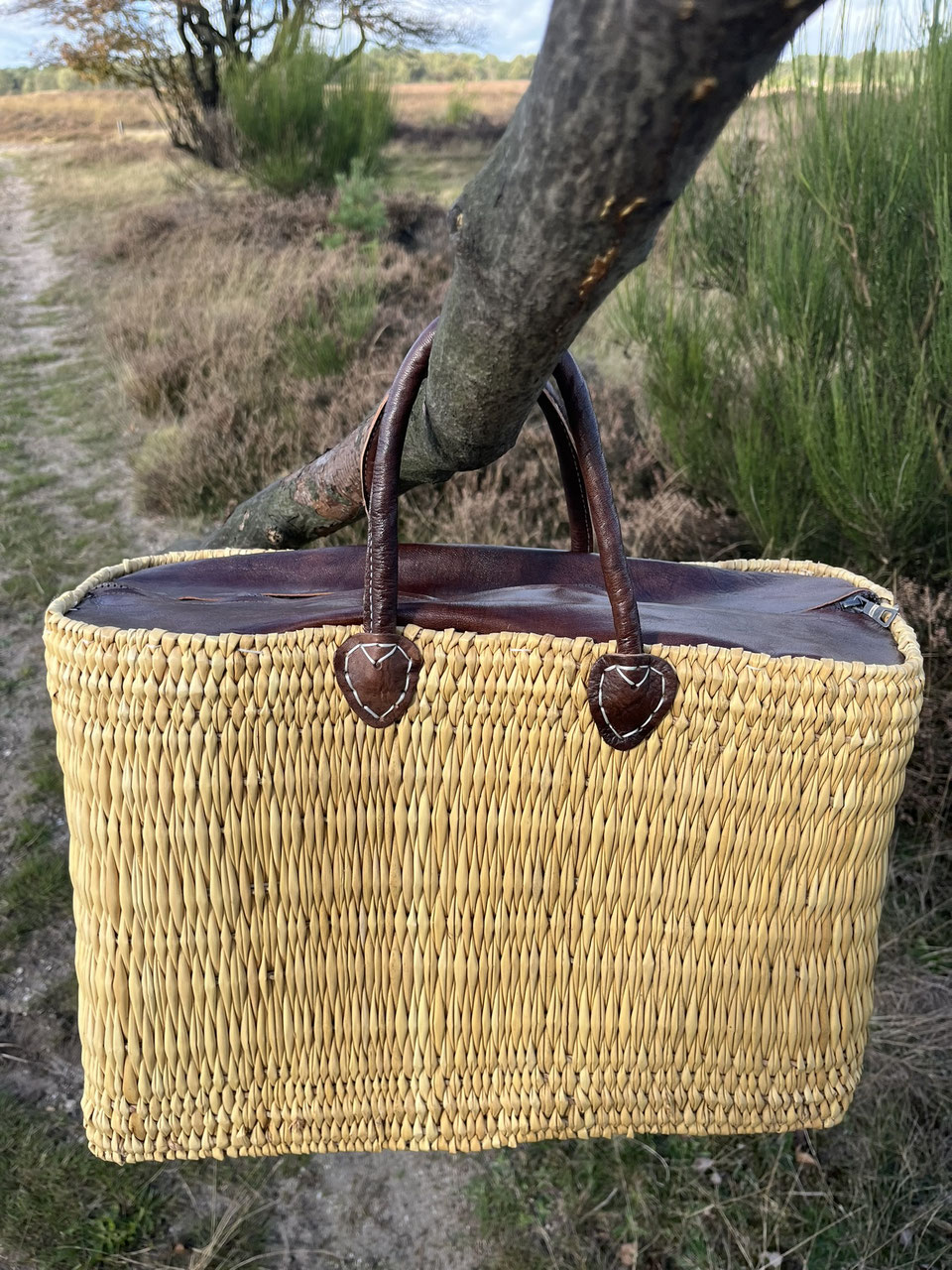 Rattan bag Faria with leather closure, hanging from a branch