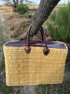 Rattan bag Faria with leather closure, hanging from a branch