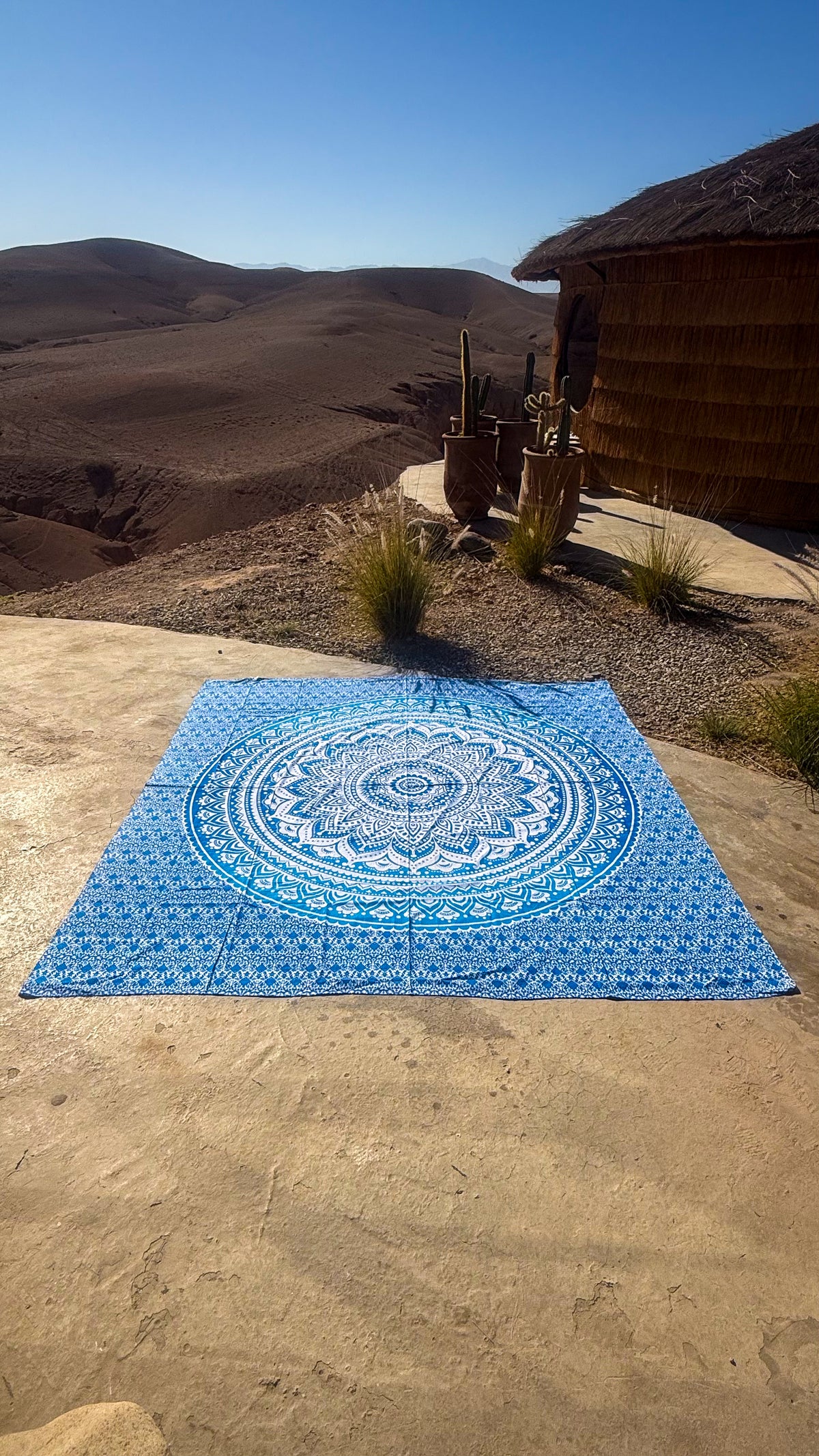 XXL strandlaken Blue Ombre 235x220 cm, uitgespreid op zandsteen onder een blauwe lucht