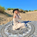 XXL strandlaken Flowerpower Black 235x220 cm, met een vrouw met hoed op het strand