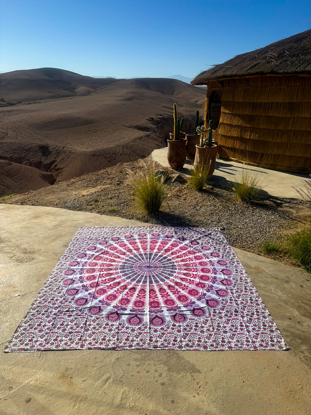 XXL strandlaken Seashell Pink 235x220 cm, uitgespreid op zandsteen onder een blauwe lucht