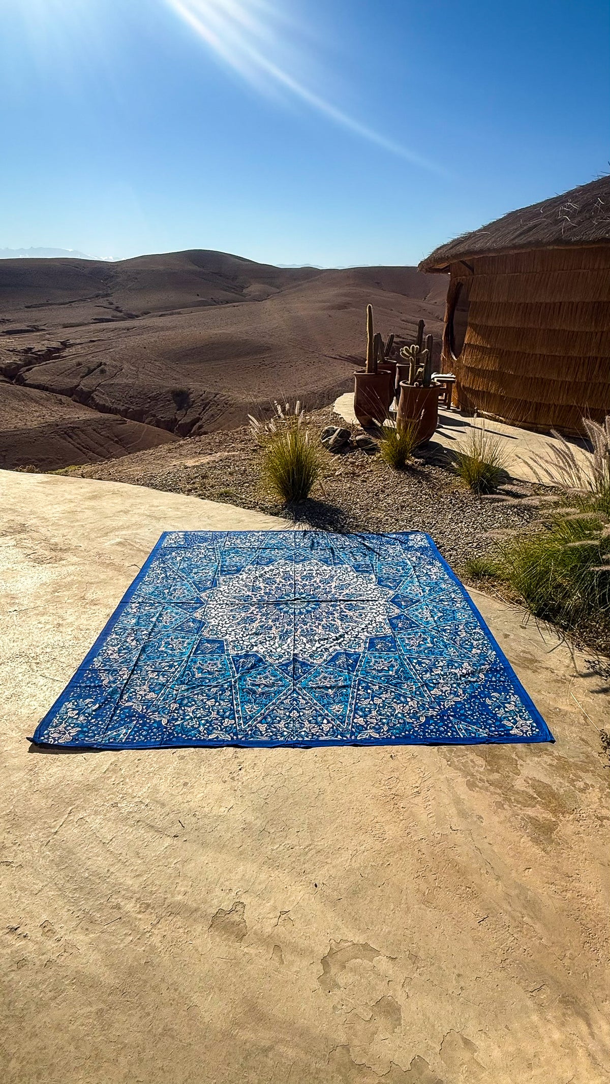 XXL strandlaken Star Blue 235x220 cm, uitgespreid op een zonnige rots met uitzicht op de bergen