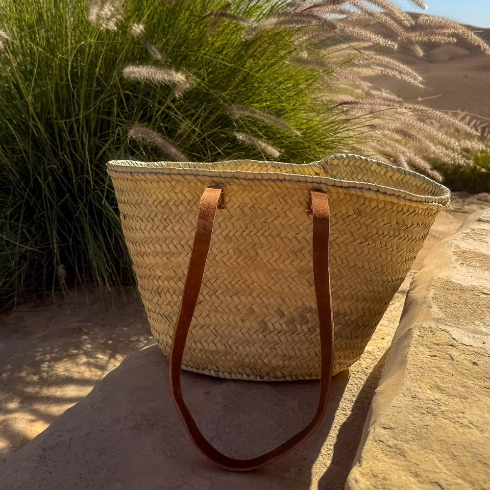 Rieten shopper met lange leren hengsels, met lange leren hengsels tussen het groen