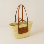 Rattan shoulder bag with leather handles and envelope pocket, front view on a light background
