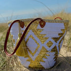 Boho rattan beach bag Aztec white and gold, side view in the dunes