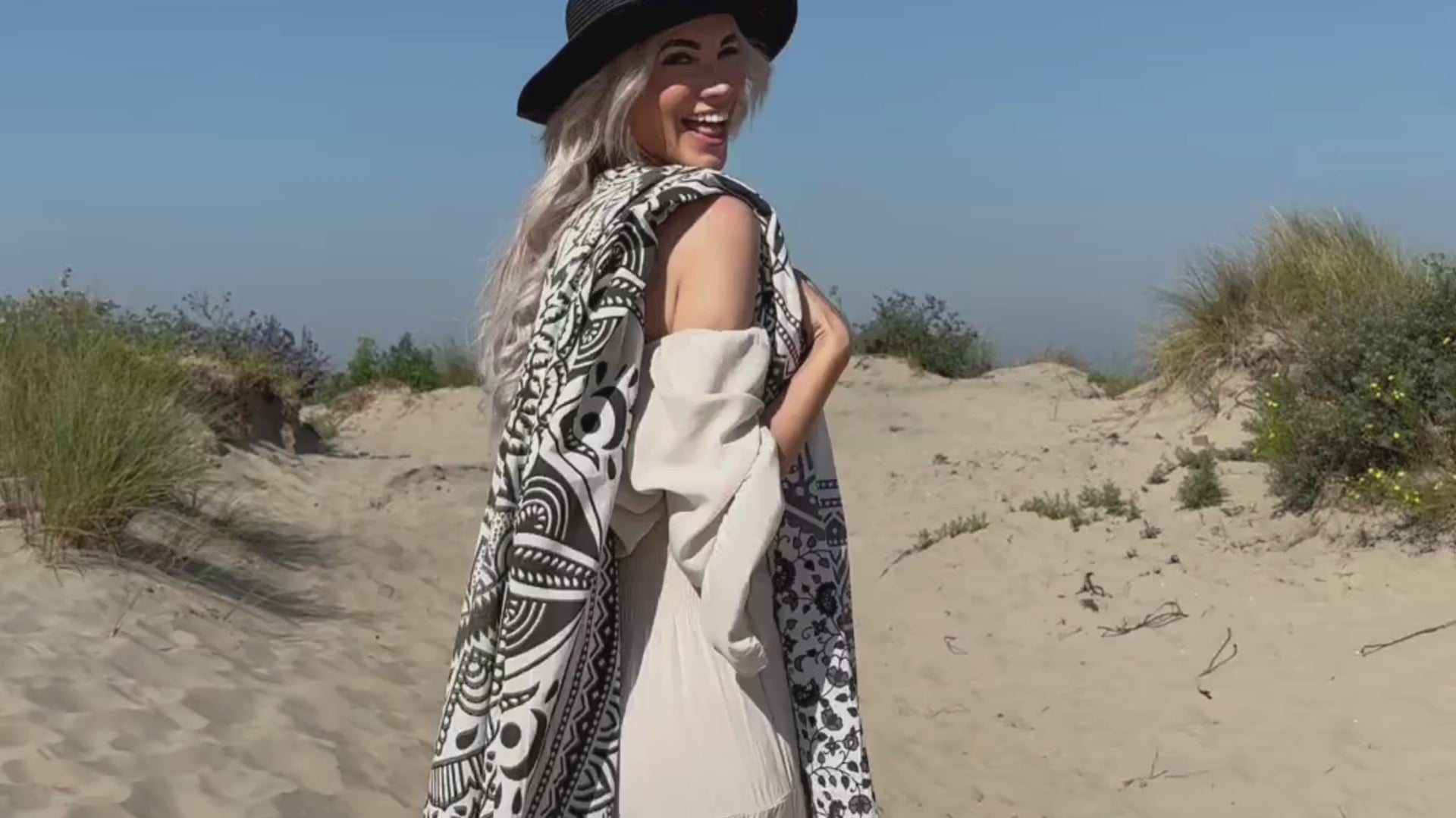 Video van een vrouw in de duinen met een zwart wit mandala strandlaken