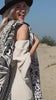 Vrouw loopt met een zwart-wit mandala strandlaken door de duinen